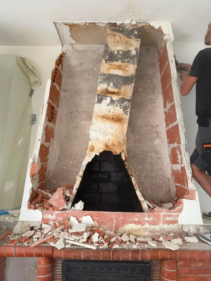 Hotte de cheminée en cours de démolition, murs protégés par des bâches, gravats sur le socle